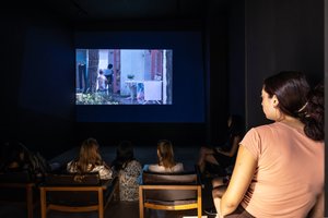 Jugendliche, die sich in einem dunklen Raum, einen Film auf der Wand ansehen.