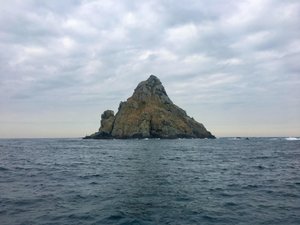 Foto einer im Meer herausragenden Felseninsel.
Photo of a rocky island jutting out into the sea.