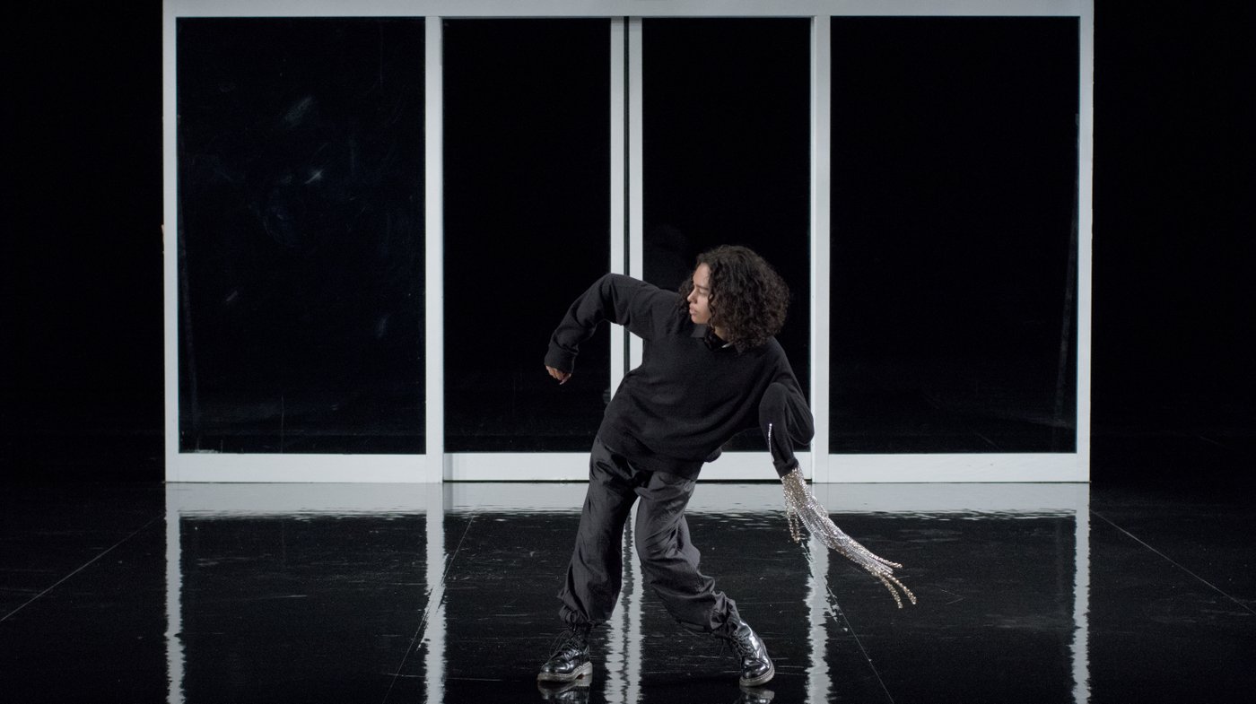 Performer in black clothes with silver chains in dancing movement