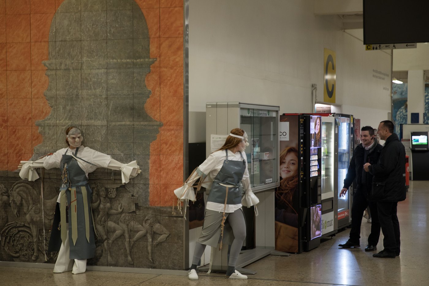 Two masked and disguised performers sneak up on two spectators.