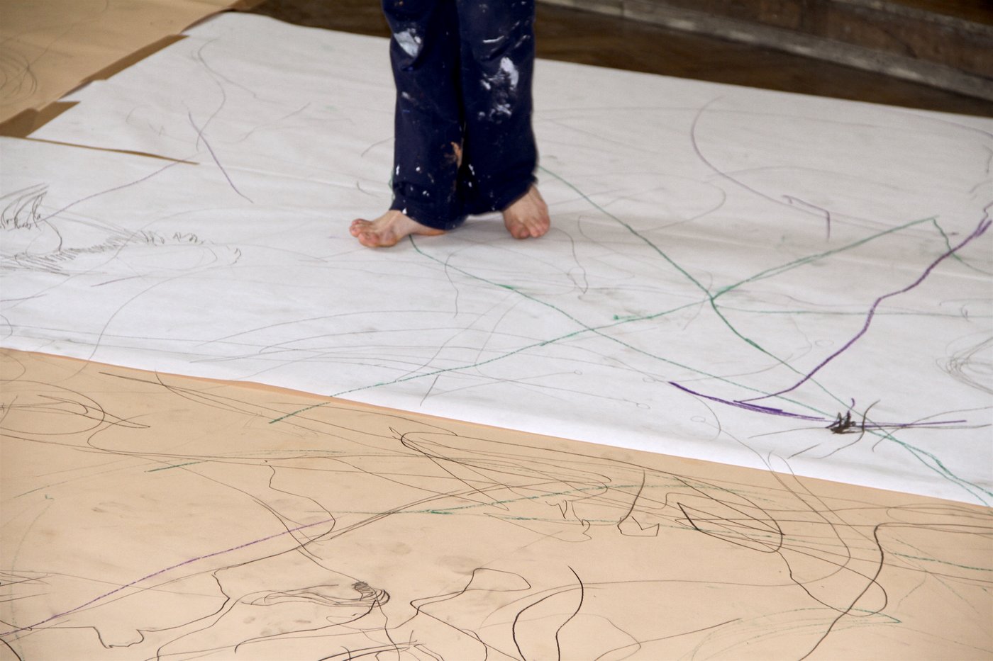 Marked sheets of paper lying on the floor and the feet of a person walking on them