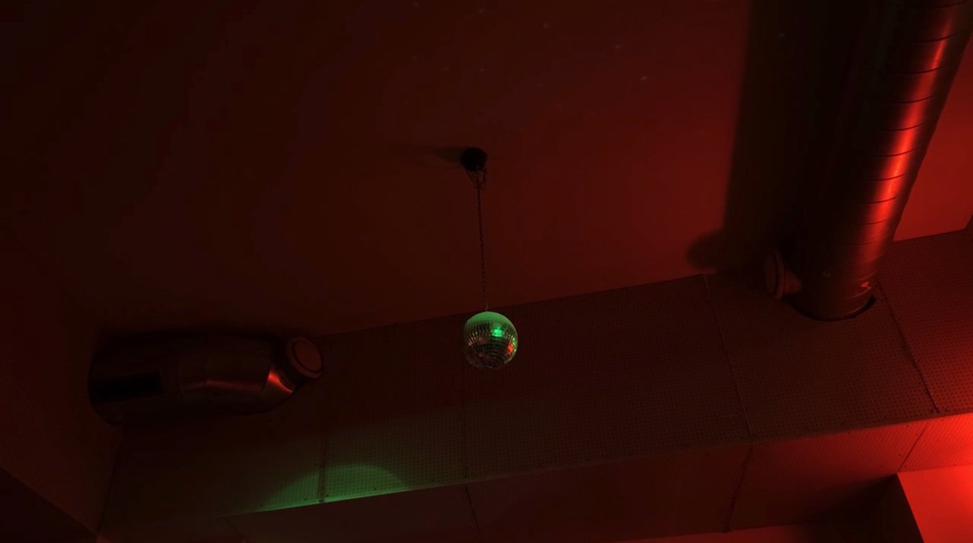 Foto einer Decke mit Abluftrohren in rotem Licht getaucht mit einer Diskokugel