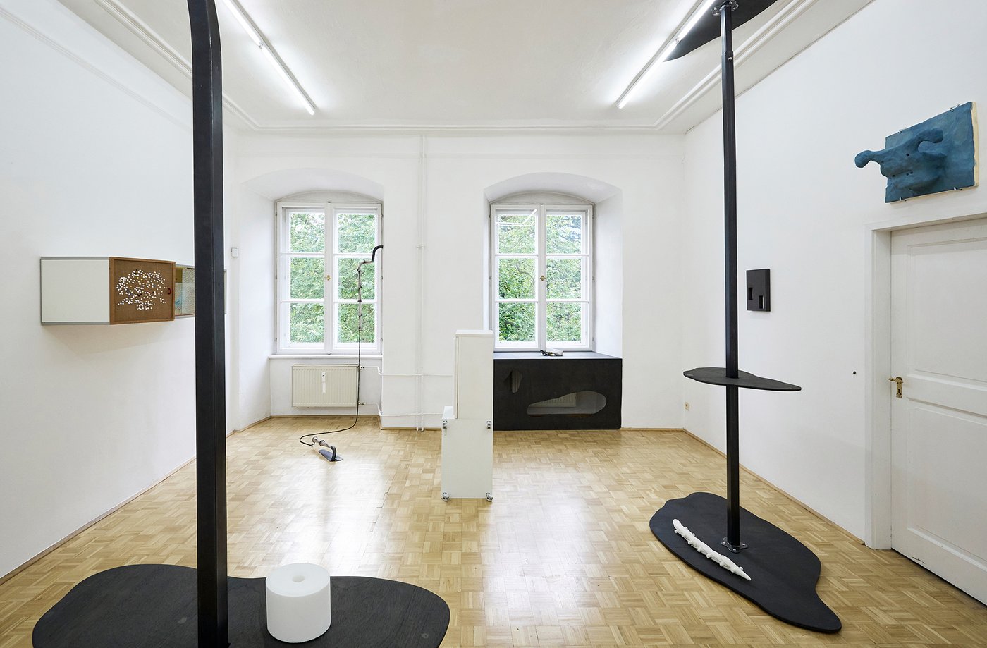 Ausstellungsansicht mit diversen Kunstobjekten in einem hellen weißen Raum
