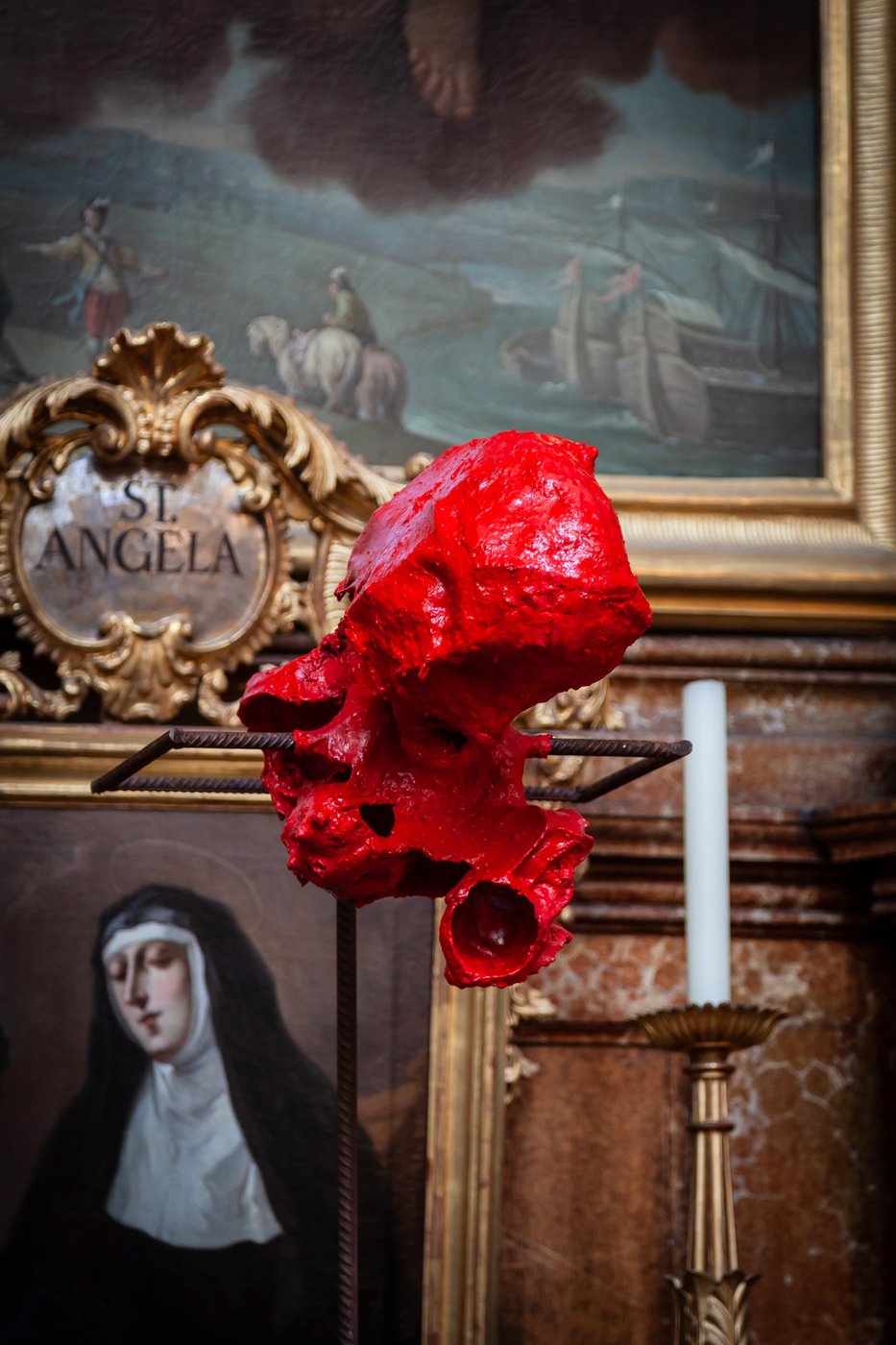 vor einem Altarbild in einer Kirche steht eine rote Kunstinstallation