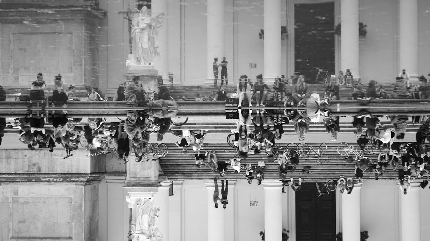 Ein Filmstil vom Film “Strahlen”. Viele Leute sind am Teich vor der Karlskirche. Das Bild ist aber ein umgekehrte Spiegelung auf der Oberfläche des Wassers des Brunnens.