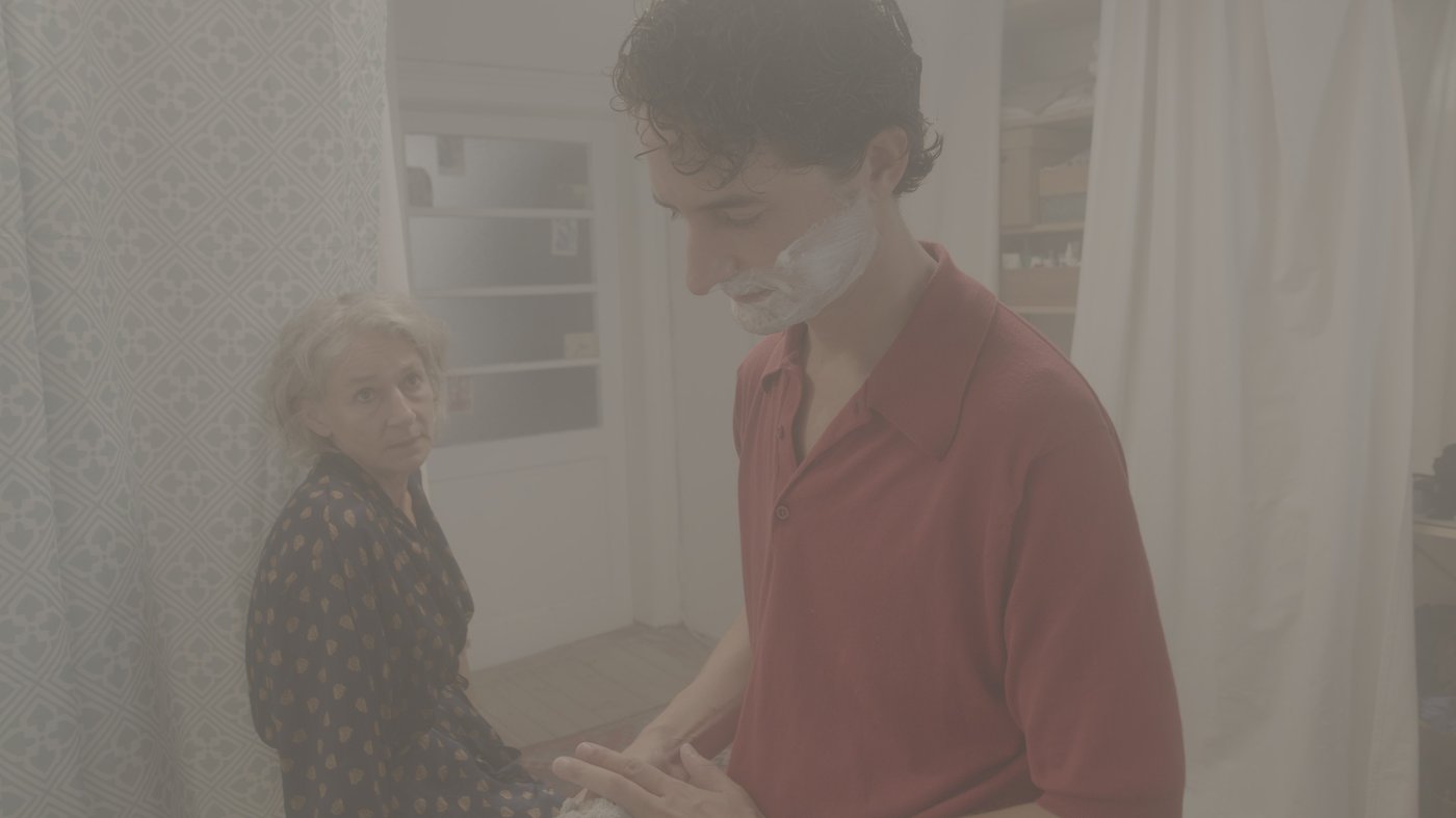 Foto von einer Frau und einem jungen Mann der sich gerade Bartschaum auf sein Gesicht aufträgt, das bild ist grau hinterlegt