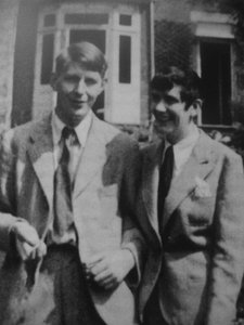 schwarz-weiß Foto von zwei Personen im Anzug die Arm in Arm stehen und lächeln