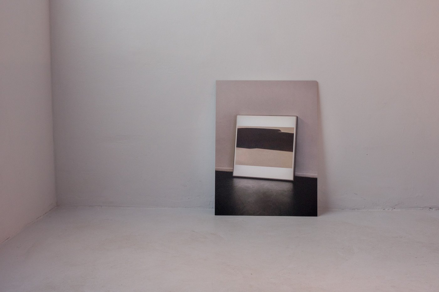 Ein Bild steht am Boden an eine leere Wand gelehnt.