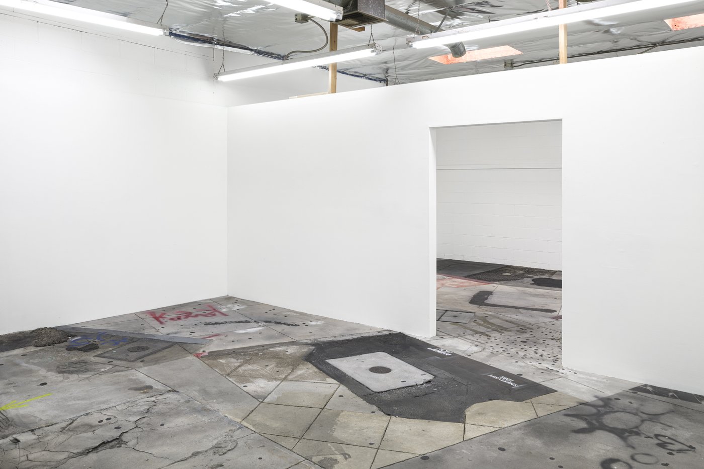 Continuous Sidewalk, 2021-23, Installationsansicht.
gegossener und geformter Beton, Gießharz und Metalleinlagen, Ziegelstein, Asphalt, Farbe, Silikon, Wachs, Sand und Schmutz, Siebdruck auf Aluminium, bestehender Raum
621 Ruberta Ave, #3, Glendale, CA 91201
Bild mit freundlicher Genehmigung der Künstlerin und Château Shatto, Los Angeles; Fotografie: Ed Mumford
Als letzte Arbeit in ihrem Atelier wurde Continuous Sidewalk im Sommer produziert und der Öffentlichkeit zugänglich gemacht.  Die Arbeit basiert auf Fotografien, die bei Spaziergängen in der Innenstadt von Los Angeles aufgenommen wurden - der Bürgersteig ist in vollem Maßstab in Beton nachgebildet - die Form ist erinnerungsähnlich - weiche Kanten, übergroße Details, partiell, nicht-linear.