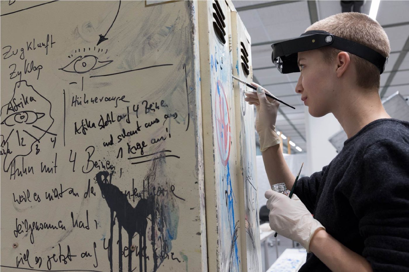 Student working with brush on a wall with inscriptions.