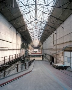 Farbfotographie eines industriellen Gebäudes, der Blick richtet sich eine Rampe hinunter.