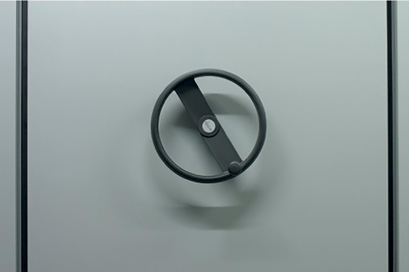 Ein Ausschnitt eines Archivregals, man sieht die graue Seitenwand und ein schwarzes Rad, mit dem das Regal bewegt werden kann.