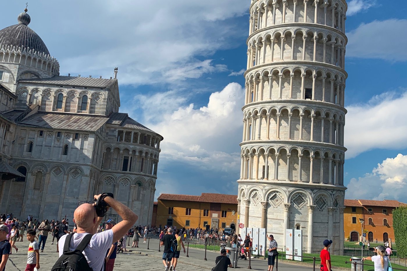 Ein weißer Mann und andere Touristen fotografieren den Turm von Pisa.