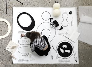 Paula Strunden sitzt auf einem großen, am Boden ausgelegten Papier und arbeitet an Entwürfen für Infra-thin Objekte.