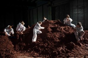 Frauen mit weißen Overalls auf einem Berg Erde