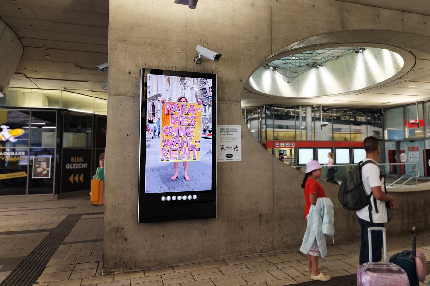Foto eines Bahnhofsplatzes mit einer Werbeanzeige im Zentrum des Bildes