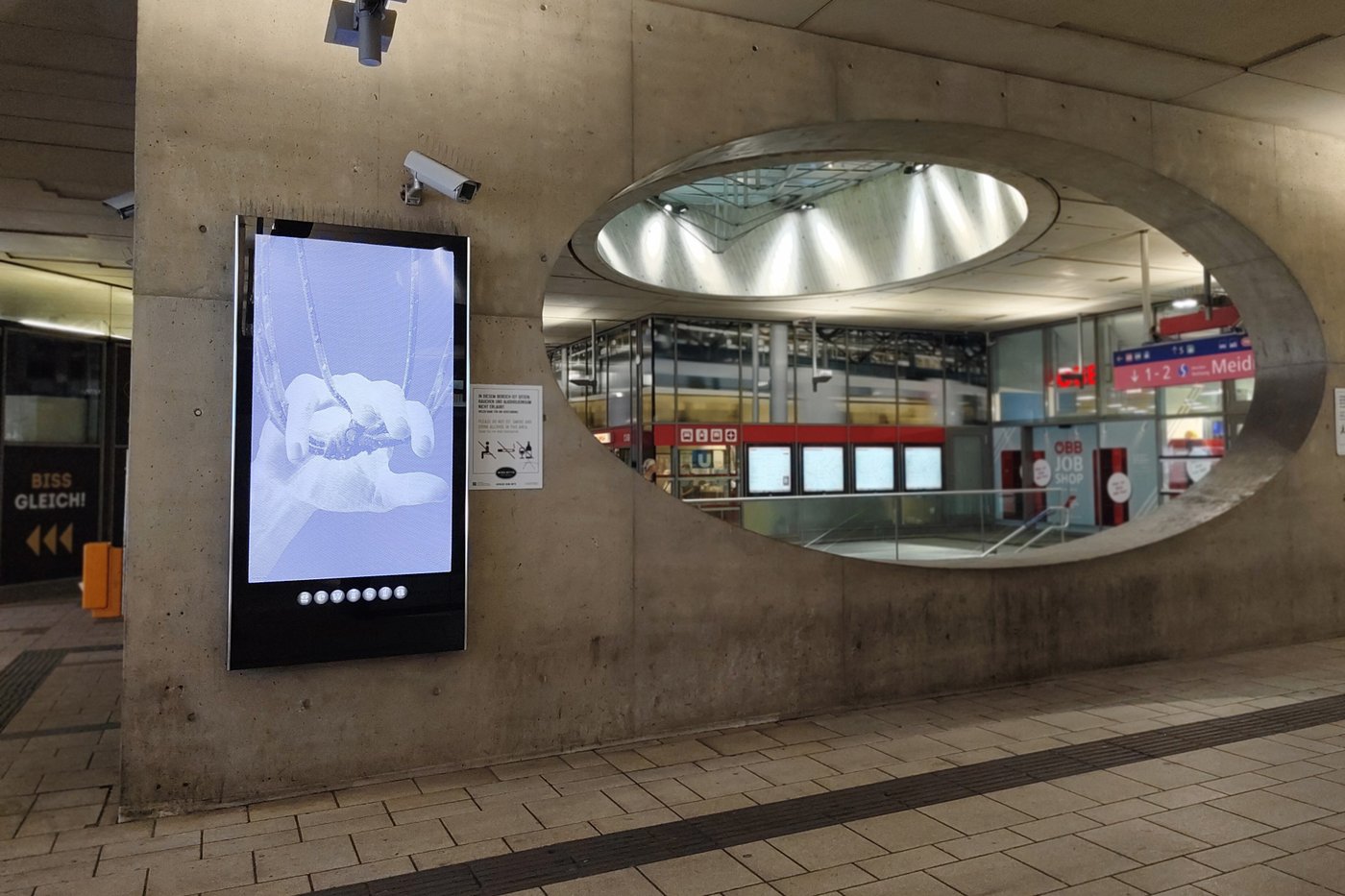 Foto eines Bahnhofsplatzes mit einer Werbeanzeige im Zentrum des Bildes