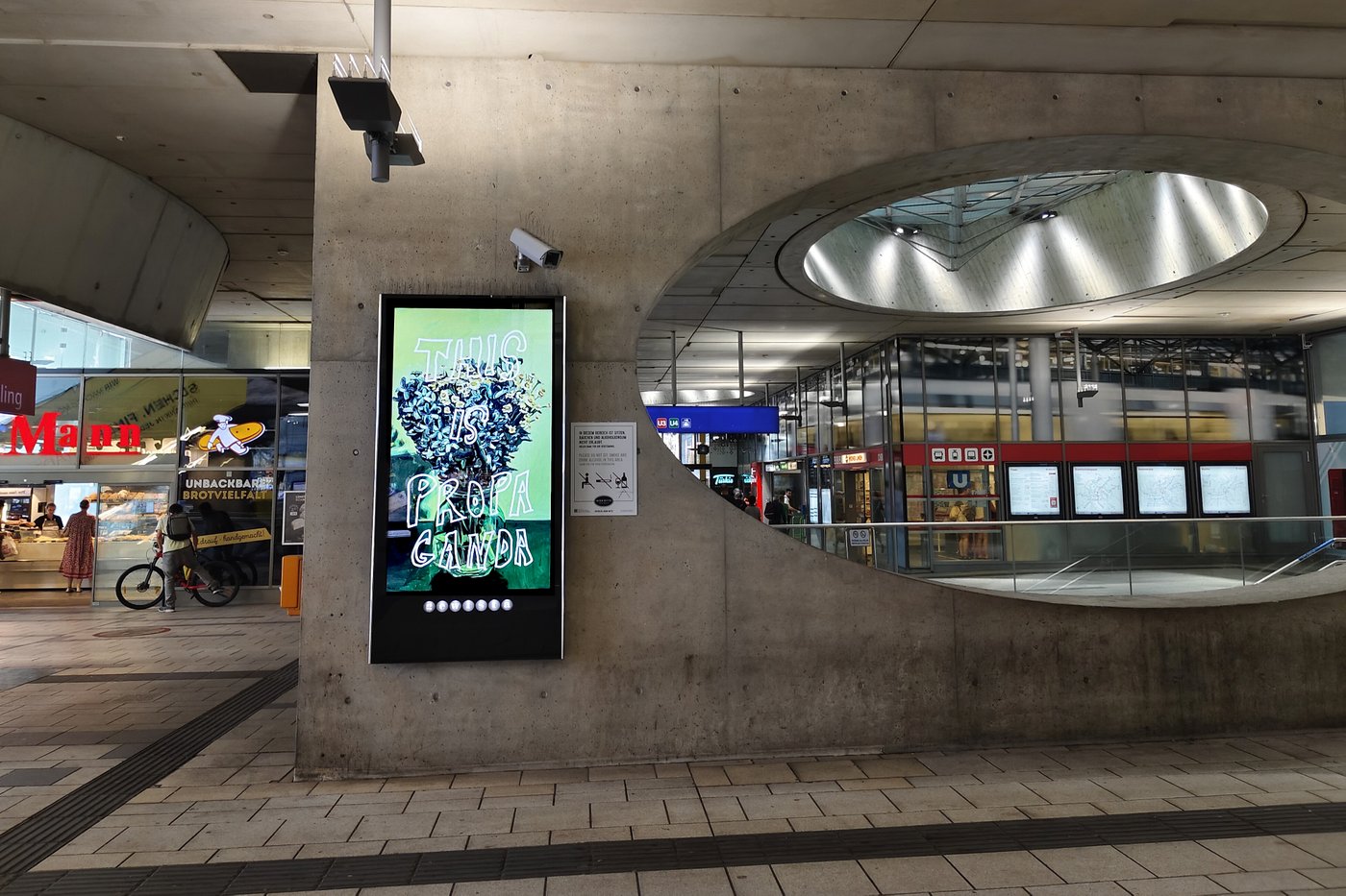 Foto eines Bahnhofsplatzes mit einer Werbeanzeige im Zentrum des Bildes