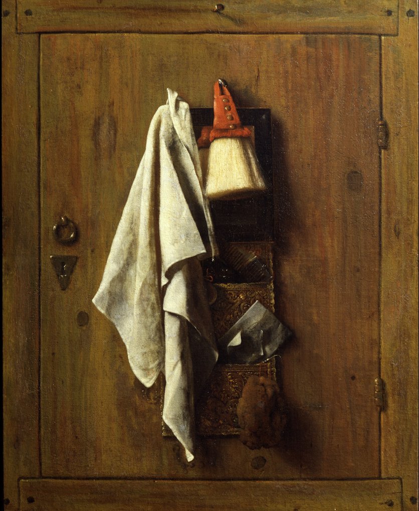 auf einer braunen Holztür hängt ein weisses Tuch, ein Pinsel und ein paar andere Utensilien