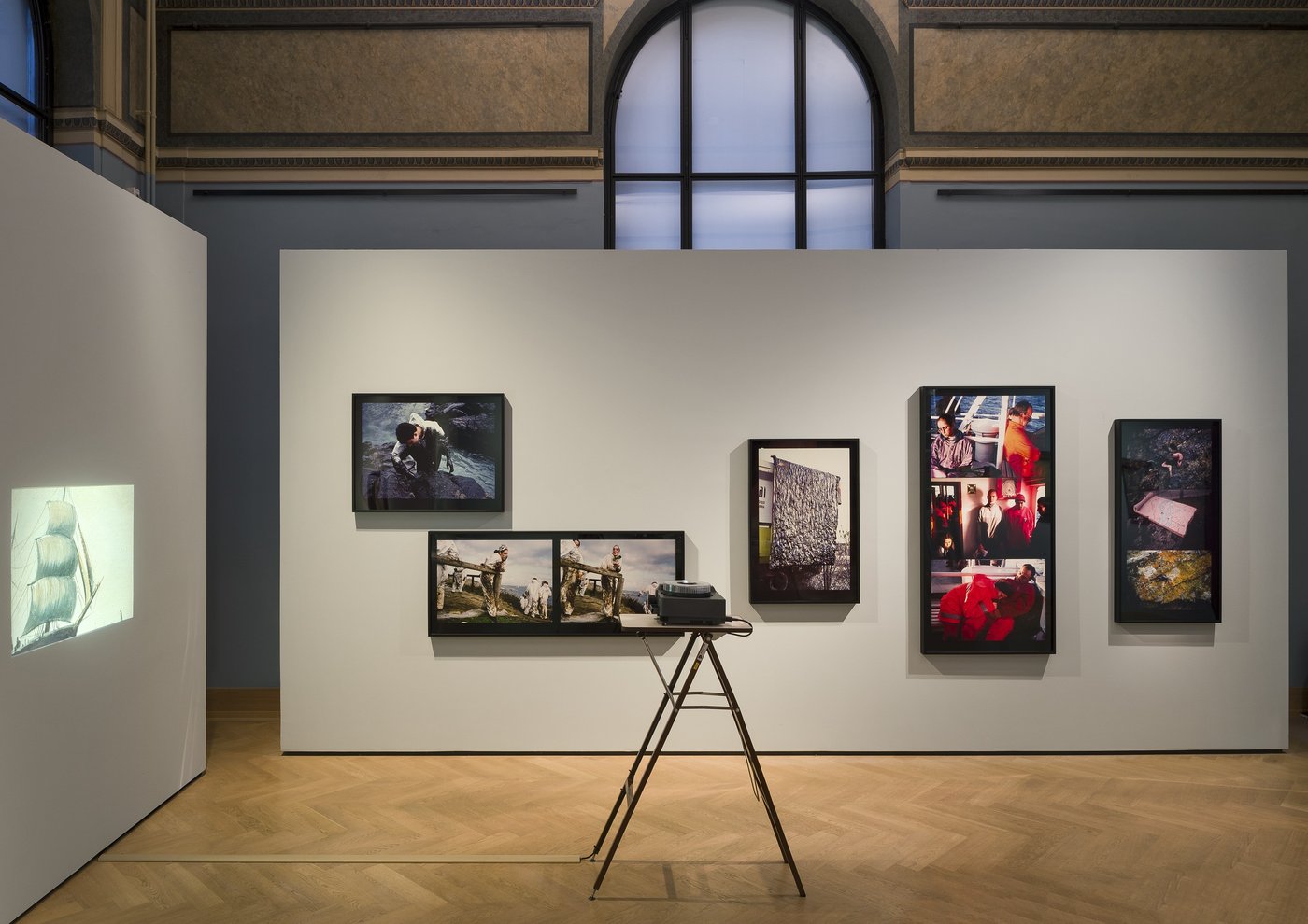 ein Ausstellungsraum mit mehreren Bildern an der Wand und einem Projektor