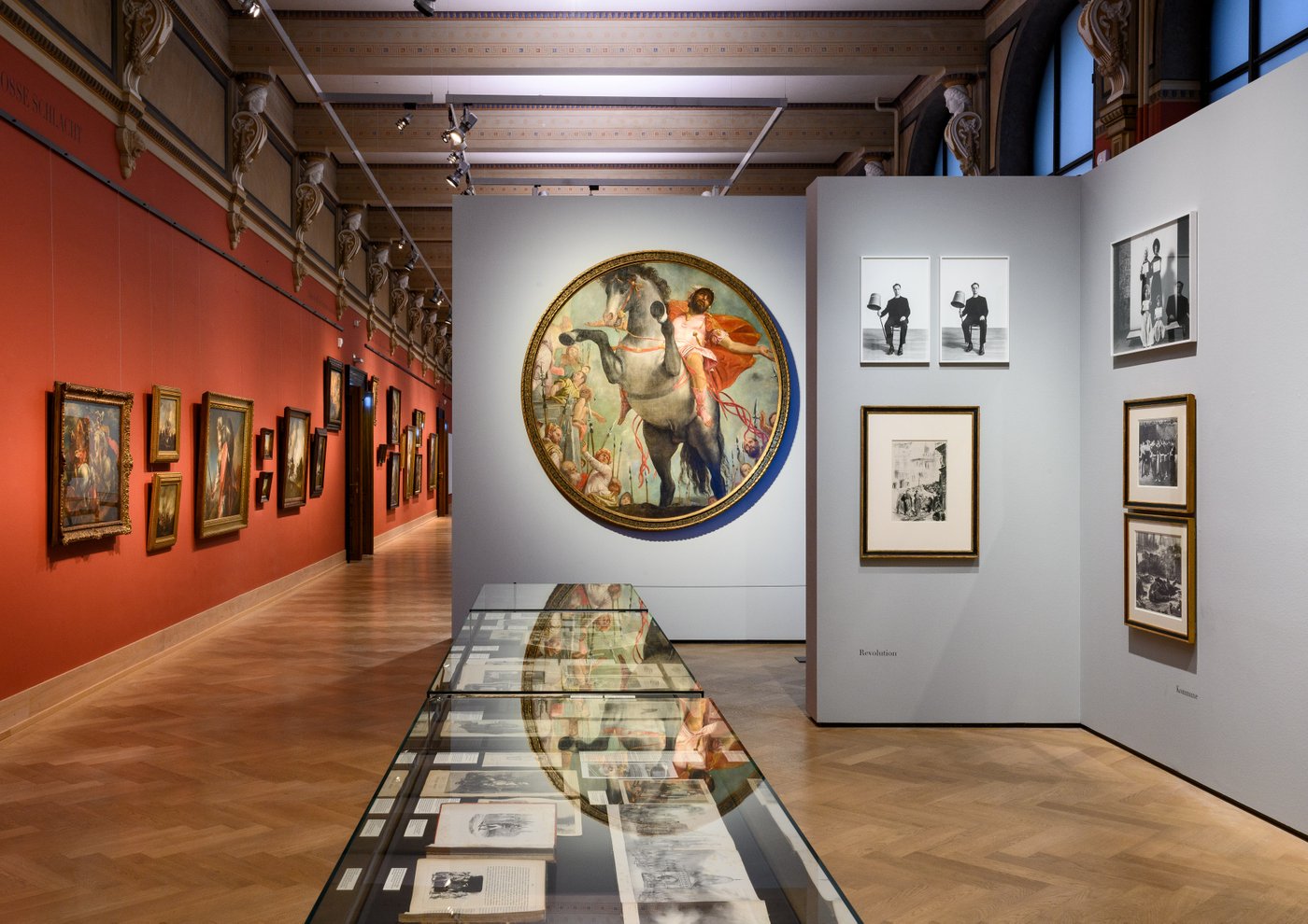 Ein langer Ausstellungsraum mit vielen Gemälden an der Wand
