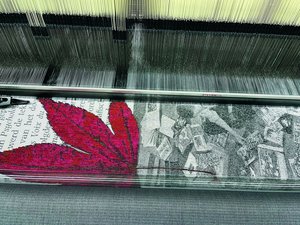 Detailansicht auf einen Webstuhl mit gewebtem schwarz weiss Sujet mit einer roten Blume