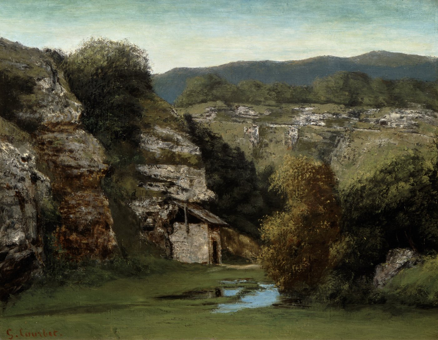 Landschaftsgemälde von Gustave Courbet: Eine grüne Flusslandschaft mit einer kleinen Steinhütte zwischen bewaldeten Kalksteinfelsen. Im Hintergrund liegen sanfte Hügel unter einem hellen Himmel. Die Szene wirkt ruhig und unberührt.