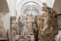 einige Skulpturen von Menschen in einer Gruppierung in einem weiss ausgemalten Kellergewölbe
