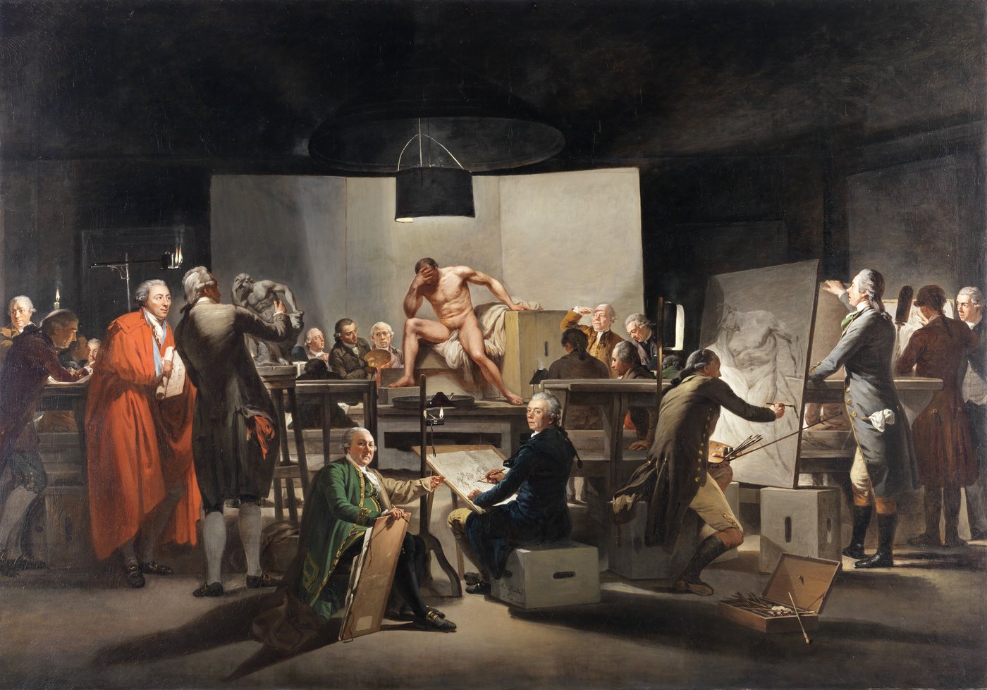 The painting shows a group of 20 elegantly dressed artists positioned in a circle around a male nude model. They are in the process of depicting him in a realistic manner. Some are painting on large canvases or drawing on sheets of paper, while others are sculpting the nude model. In the room there are several wooden standing tables and crates with oval openings, allowing them to be carried. These objects serve as shelves, seats or holders for canvases. The male nude model is on a pedestal in the middle of the room. He is sitting with his legs spread on wooden crates, over which a white fabric is draped, holding his head. His face is not visible. He has short brown hair, which distinguishes him from the other men, who wear white powdered baroque wigs with curly rolls. It is evening and the room is lit with multiple=