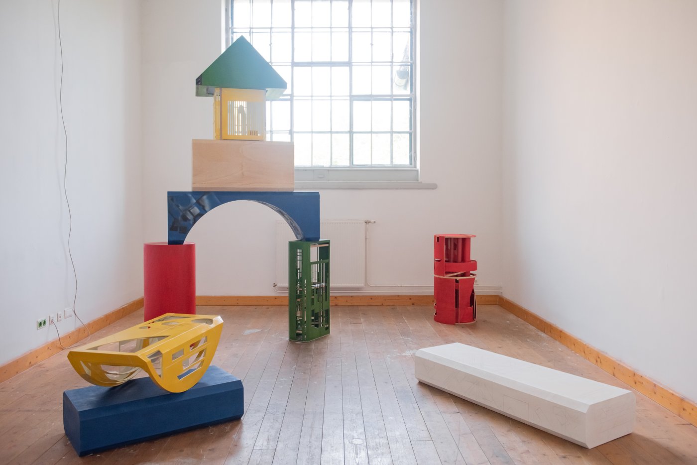 Ausstellungsansicht mit bunten großen Bauklötzen, die eine Art Kinderhaus ergeben