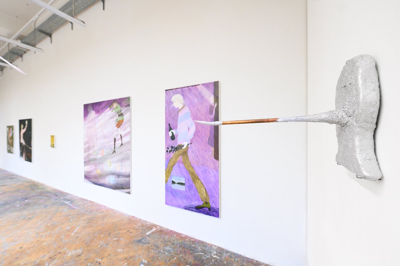 Kunstwerke an weißer Wand, im Vordergrund Ein Werk aus Alufolie