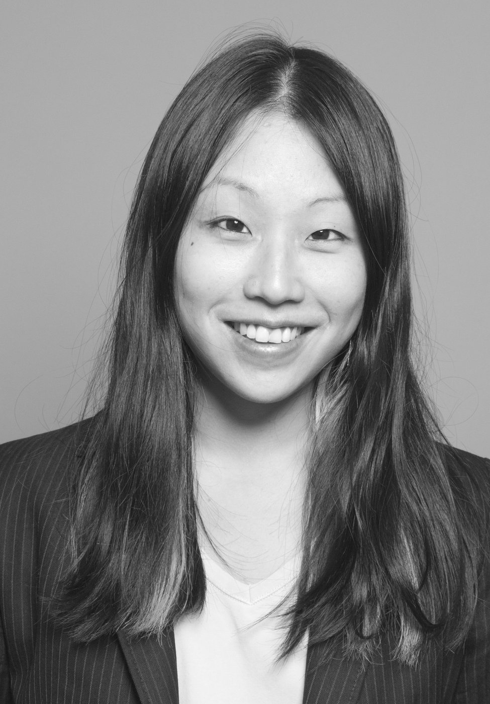 schwarz-weiß Foto einer asiatischen Frau mit langen Haaren die in die Kamera lächelt