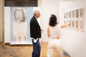 Ausstellungsansicht mit Kunstwerken auf Stellwänden und Personen die diese betrachten