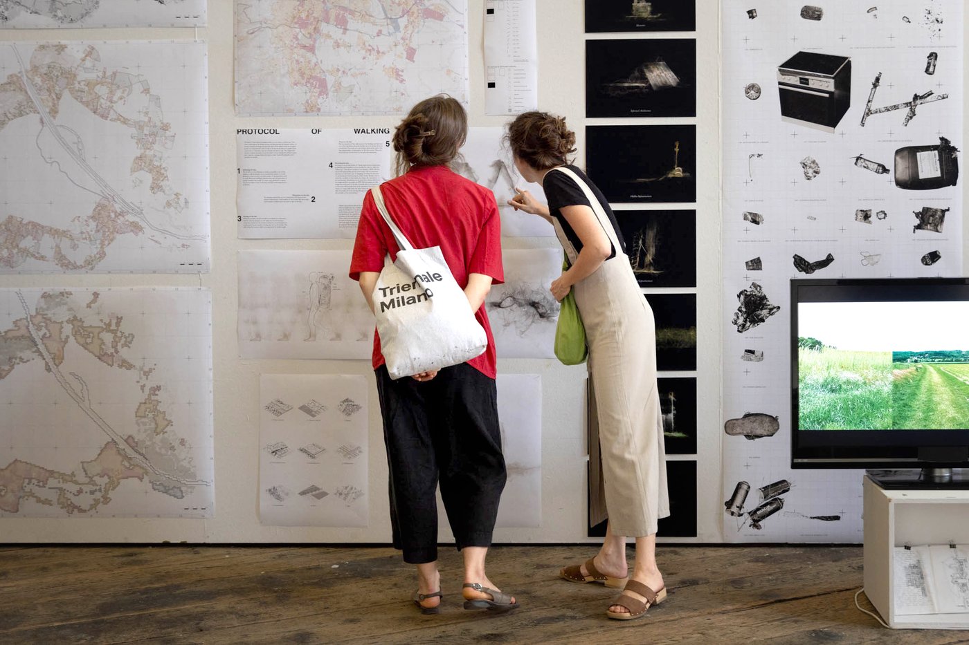 Personen vor einer Ausstellungswand betrachten Architekturzeichnungen