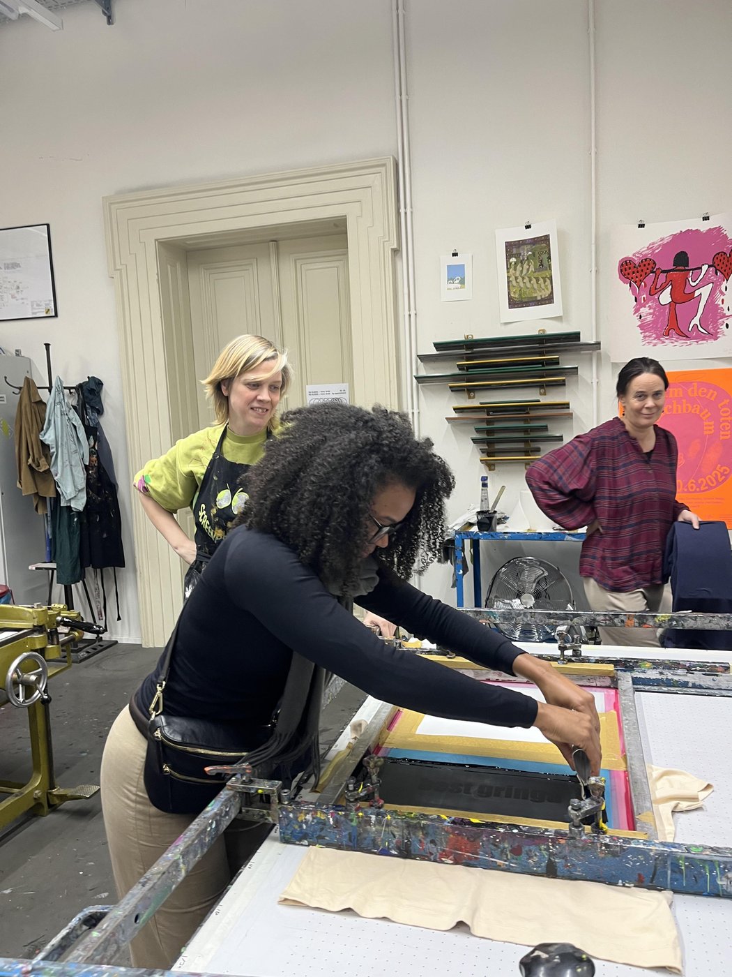 Person arbeitet an einer Siebdruckanlage in einer Werkstatt.