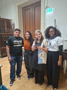 Vier Personen stehen in einer Werkstatt und lachen in die Kamera.