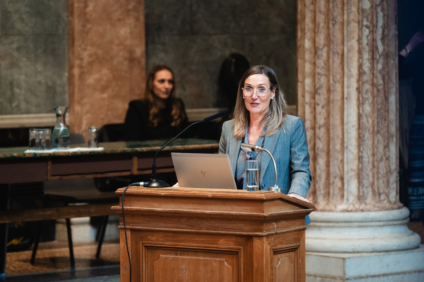 Eine Person steht an einem Pult und hält einen Vortrag.