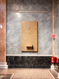 An einer Wand befindet sich ein leerer Sockel, wo einst eine Statue stand.