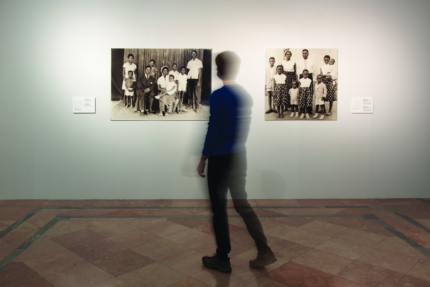 Eine blonde Frau steht vor 2 Familienbildern