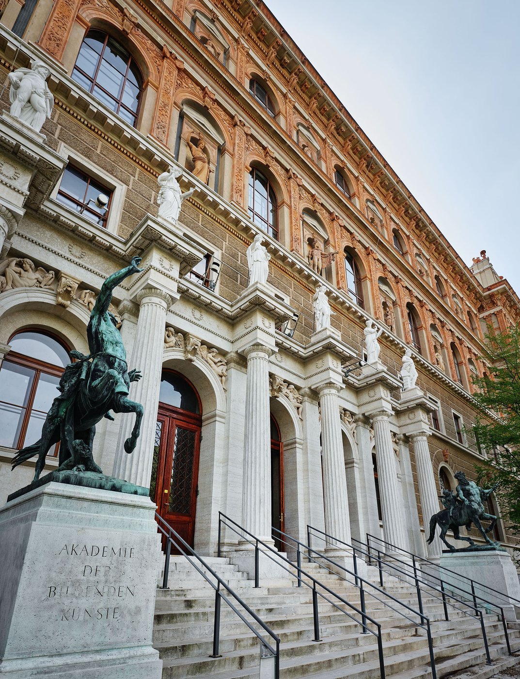 Bild von der Fassade des Akademiegebäudes am Schillerplatz, Statuen, Aufnahme von links unten nach rechts oben