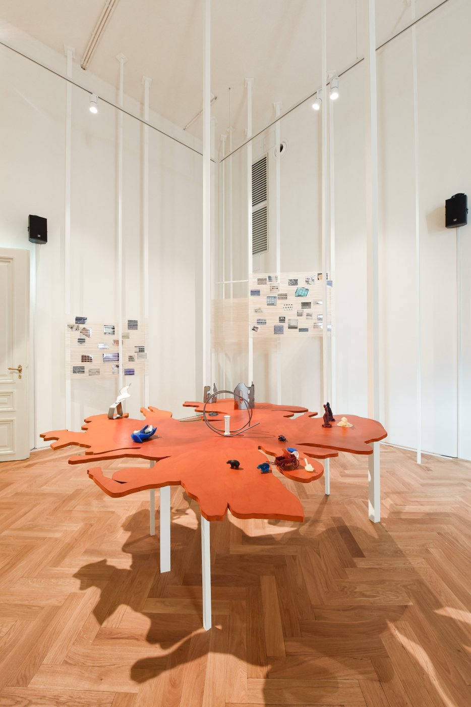 Ausstellungsansicht mit einer orangefarbenen Installation in Tischform