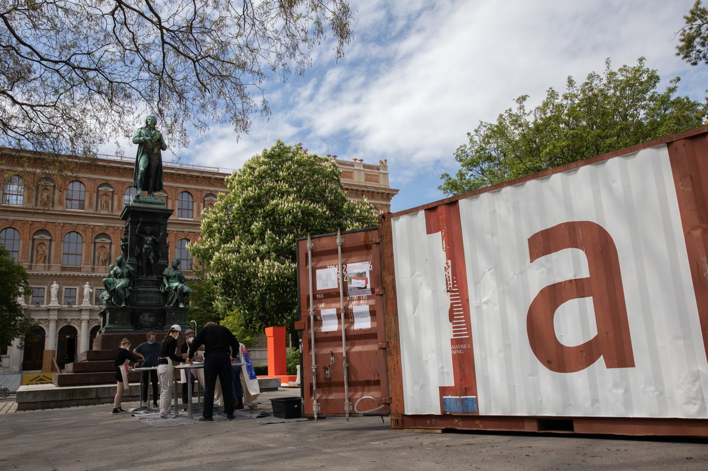 Ein Frachtcontainer steht auf einem sonnigen Platz in Wien vor dem Gebäude der Akademie
