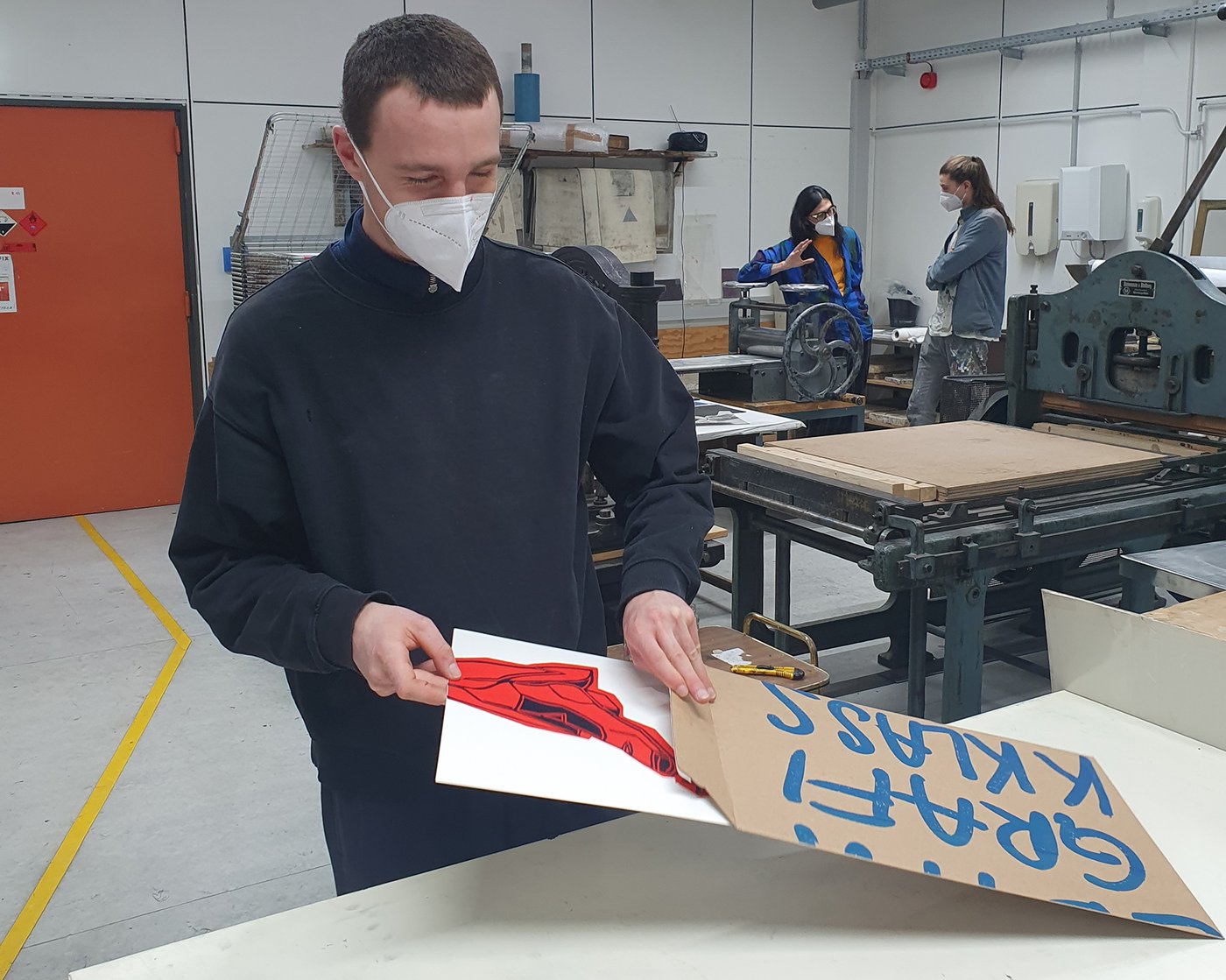 Ein Student legt ein Blatt mit einem roten Druck darauf in eine Mappe