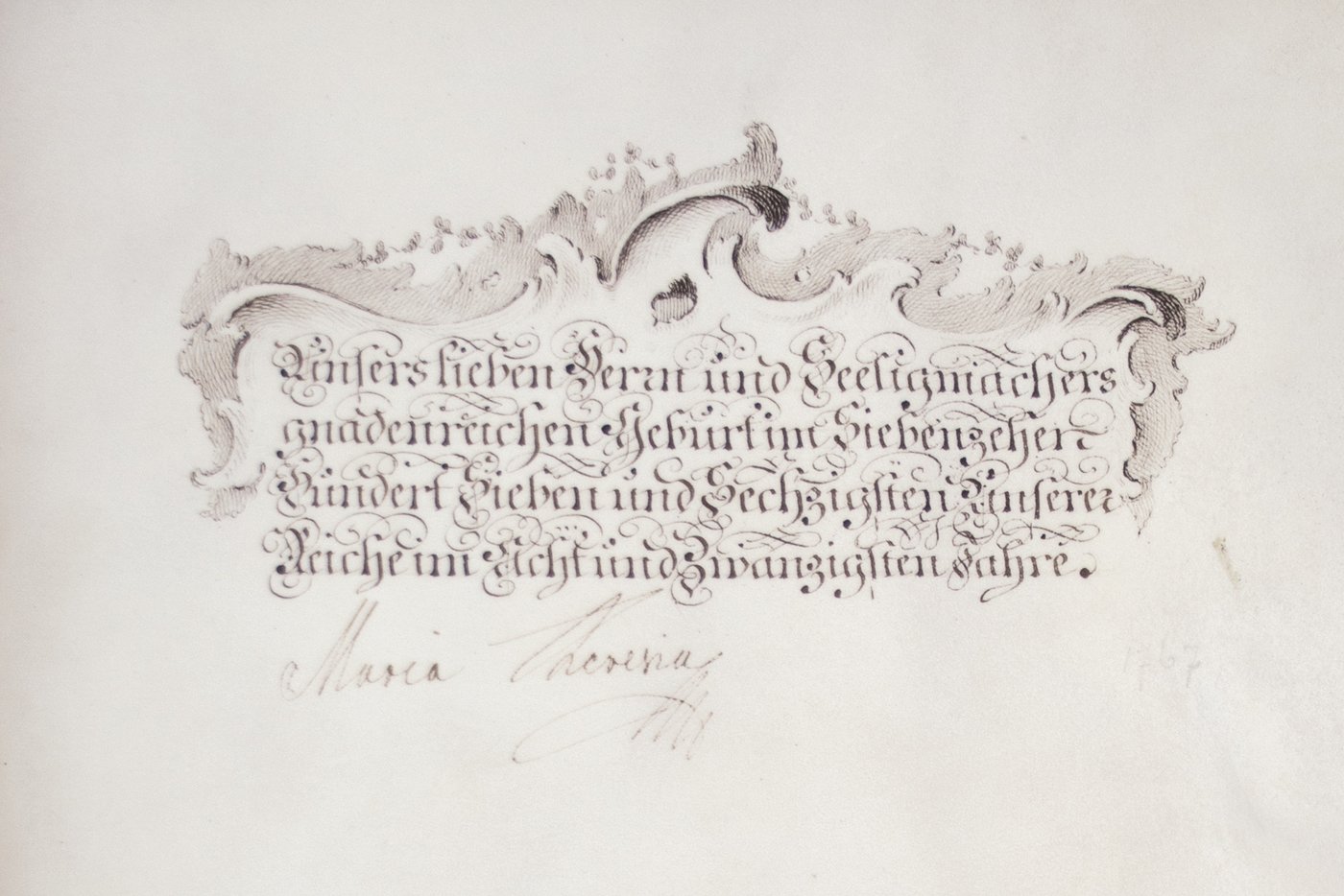 Detail der letzten Seite eines Buchs mit dem Datum des Statuts, braune Tinte auf Pergament, verschnörkelte Schrift und darüber ein Ornament, darunter die Unterschrift Kaiserin Maria Theresias.