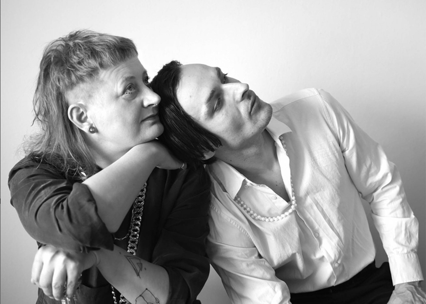 Die SW-Fotografie im Querformat zeigt das Musikerduo im Profil. Links ist Martti Winkler in dunklem Langarmshirt. Das blonde Haar trägt sie vorne kurz und hinten lang, im Ohr einen Tunnel-Ohrring. Andi Lechner im weißen Hemd hat mittellanges dunkles Haar und seinen Kopf an Marttis linke Schulter gelehnt.