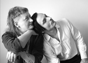 Die SW-Fotografie im Querformat zeigt das Musikerduo im Profil. Links ist Martti Winkler in dunklem Langarmshirt. Das blonde Haar trägt sie vorne kurz und hinten lang, im Ohr einen Tunnel-Ohrring. Andi Lechner im weißen Hemd hat mittellanges dunkles Haar und seinen Kopf an Marttis linke Schulter gelehnt.