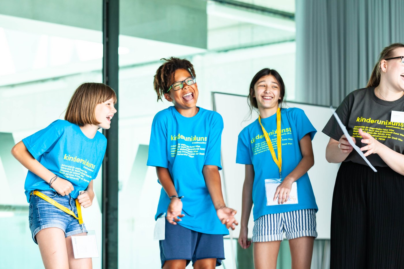 Drei lachende Kinder in blauen Shirts