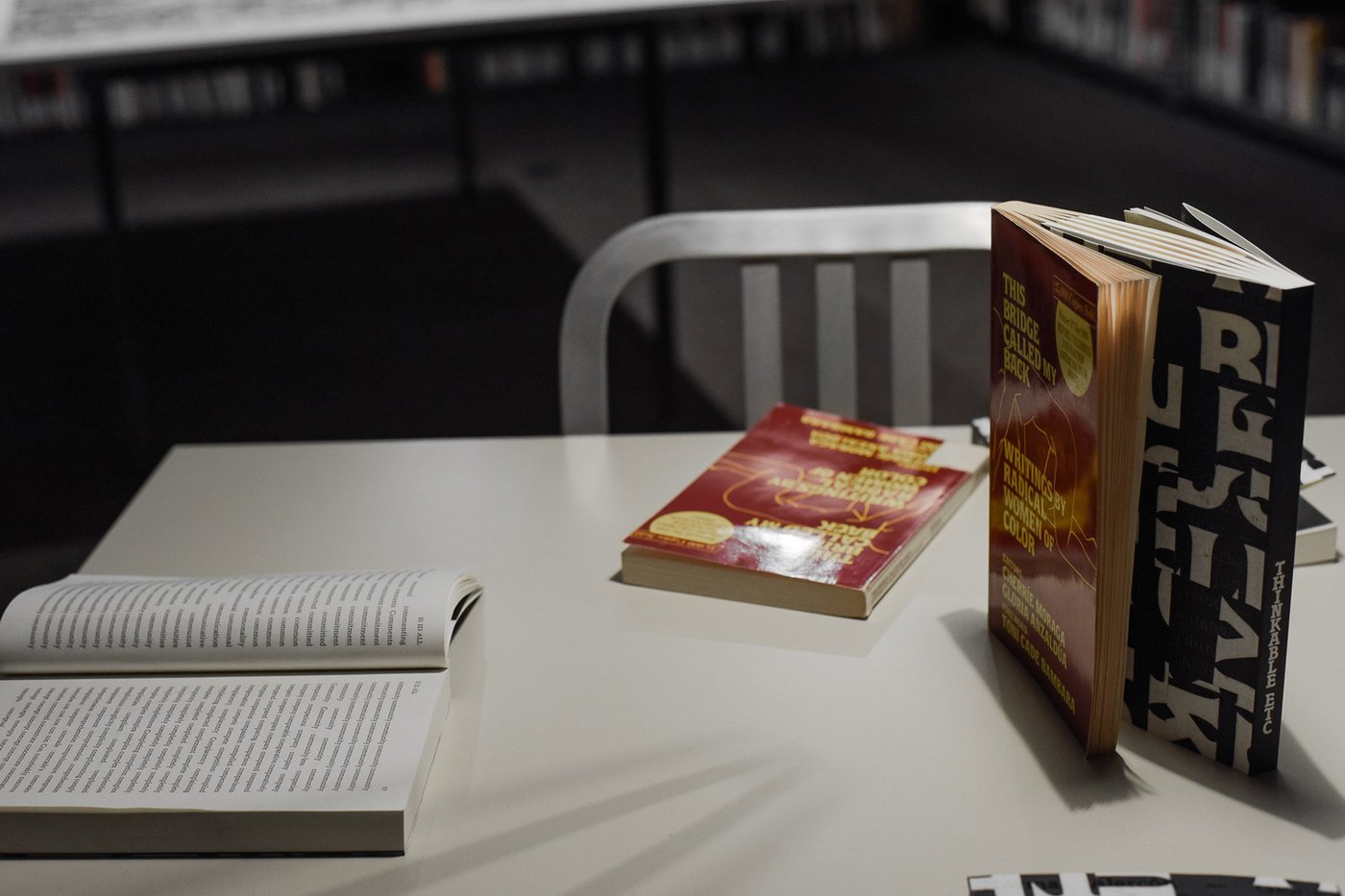 Several books presented on a table. Two books are intertwined on the open side.