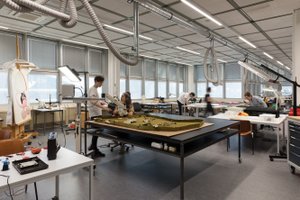 View into a large, bright studio space with several work tables, students working at some.