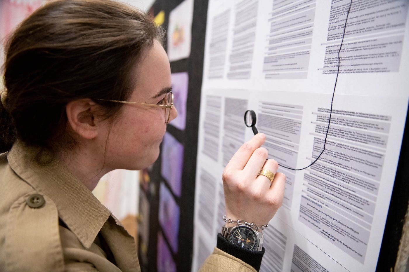 woman looking through a small magnifier on a wall full of papers